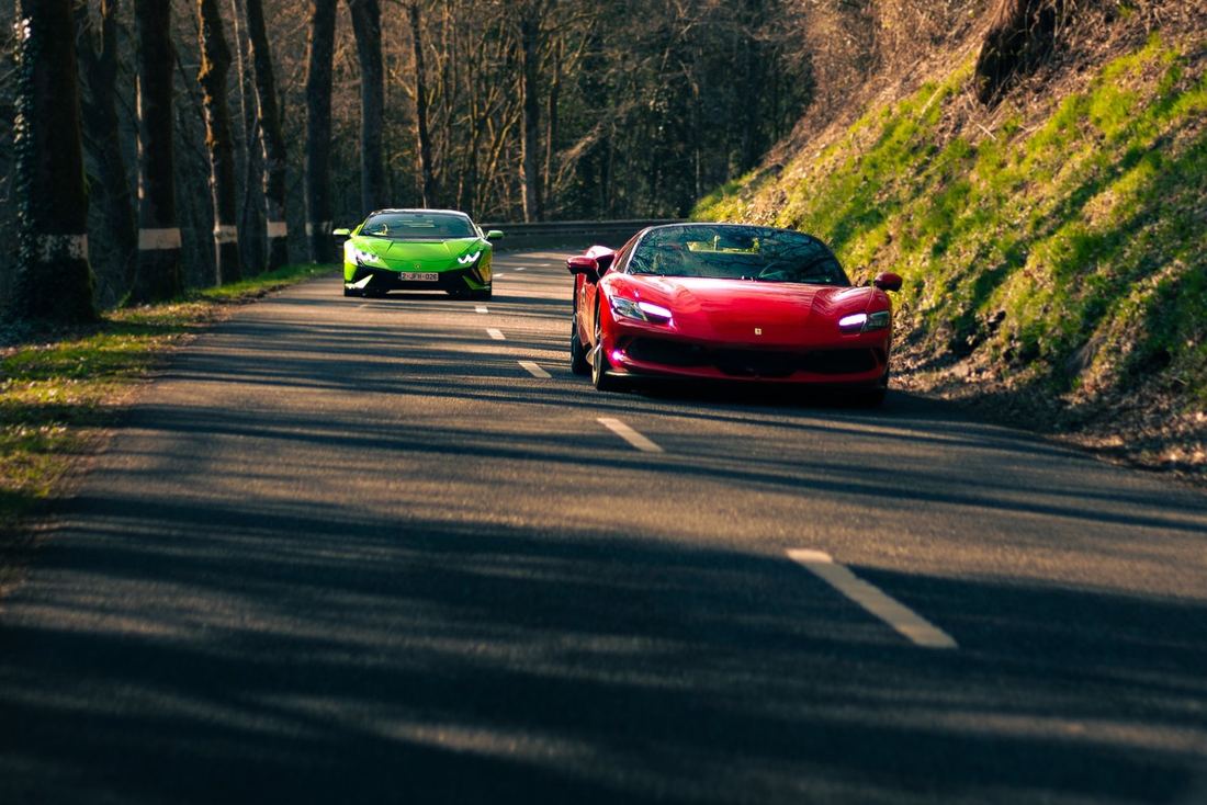 Rode Ferrari 296 en groene Lamborghini op een bosweg in Luxemburg