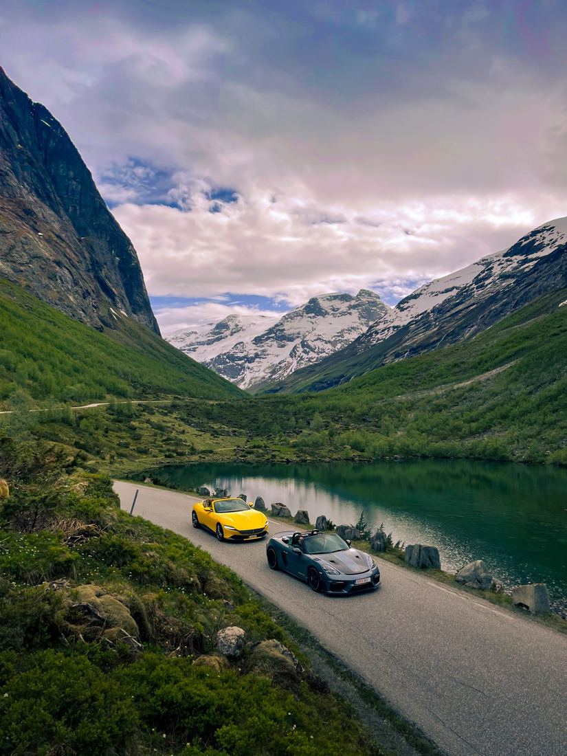 Gele Ferrari Roma en grijze Porsche Spyder langs een bergmeer