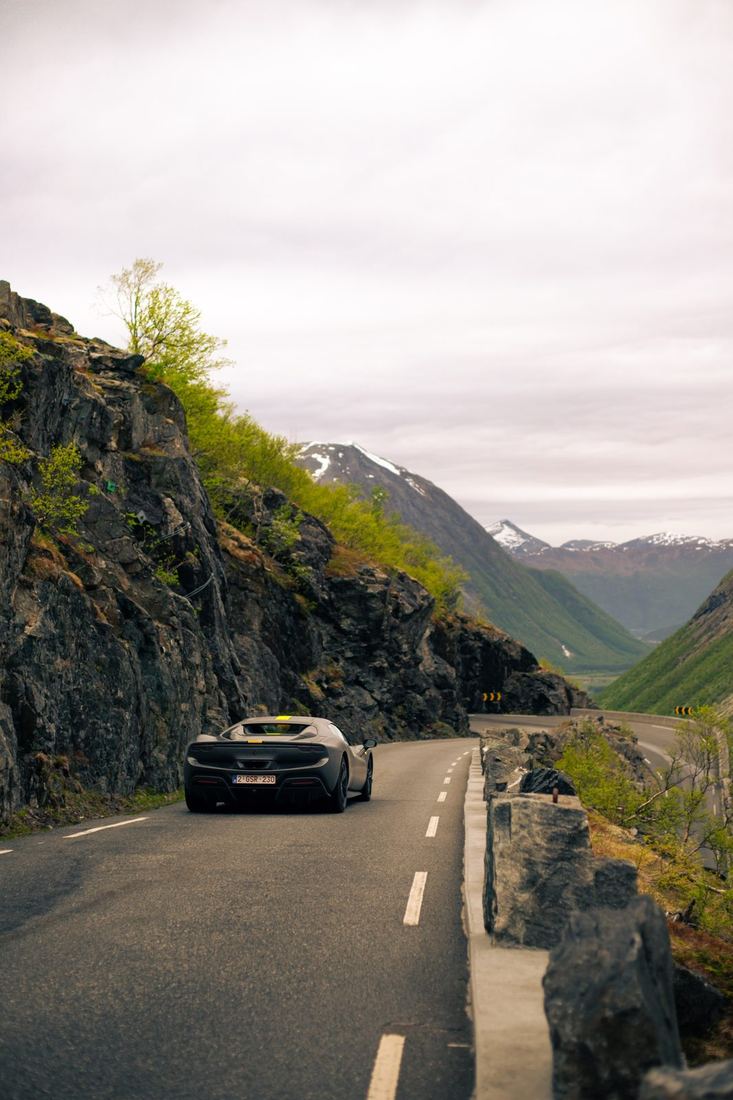 Grijze Ferrari 296 GTS van achteren op een bergweg