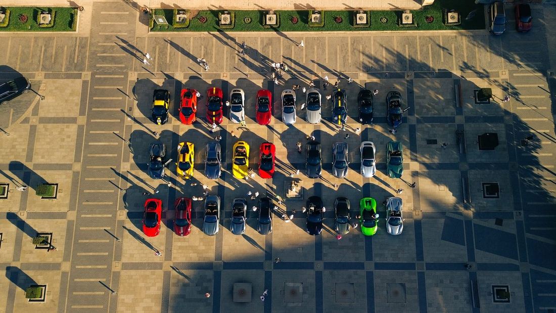 Luchtfoto van een dertigtal supercars in rijen op een plein