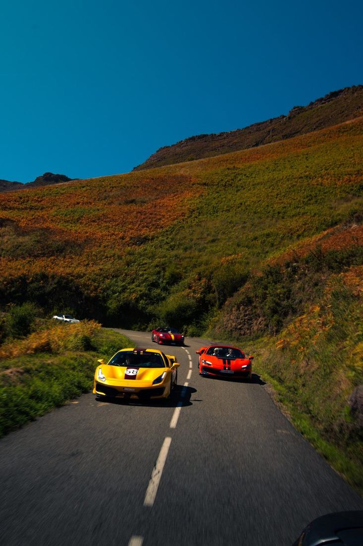Drie Ferrari’s op een bergweg tussen herfstkleurige heuvels
