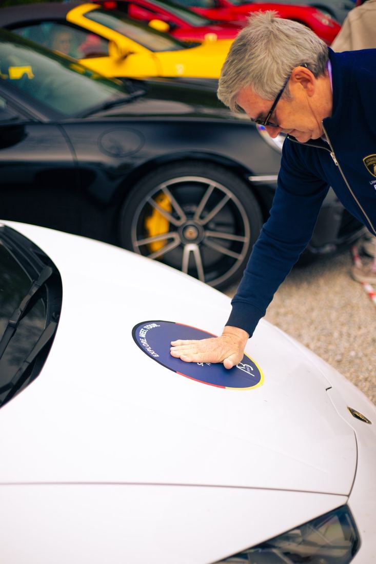 Deelnemer kleeft de AB Events-sticker op een Lamborghini