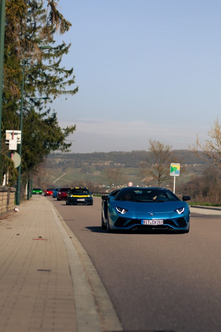 Blauwe Lamborghini Aventador voorop een colonne supercars