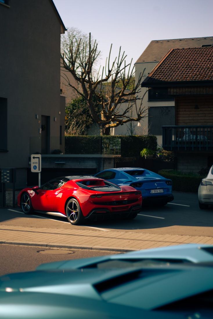 Rode Ferrari 296 en blauwe Ferrari 812 geparkeerd in het dorp