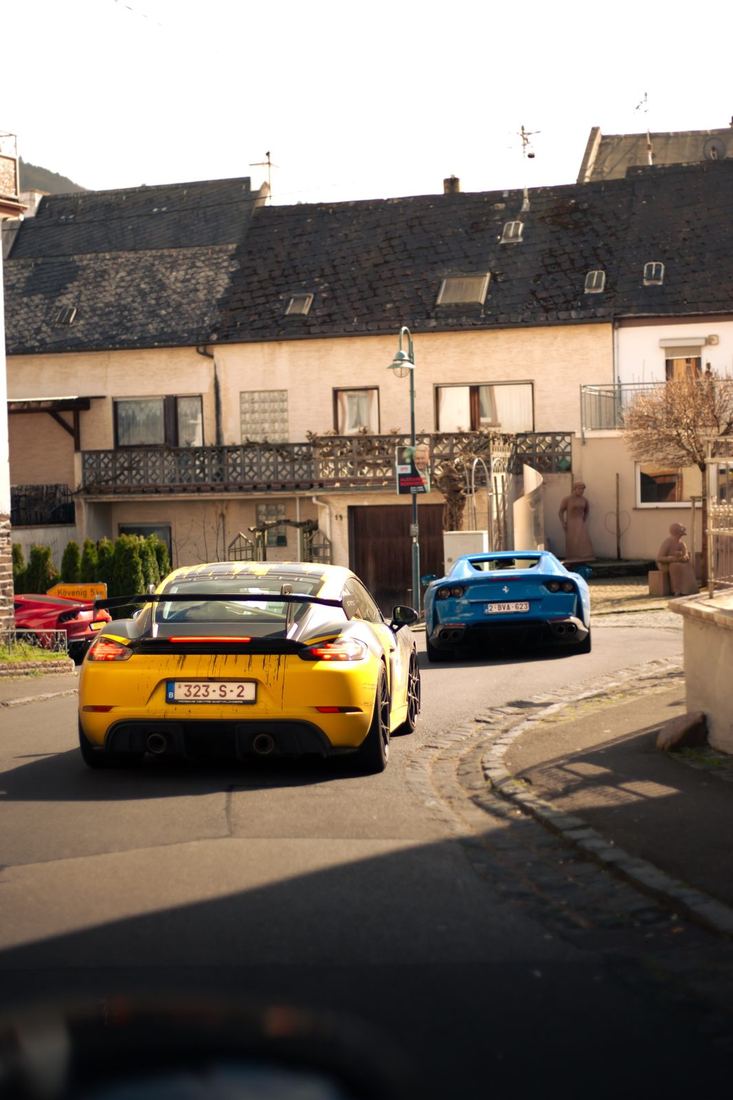 Gele Porsche Cayman GT4 RS en blauwe Ferrari 812 in een Moezeldorp