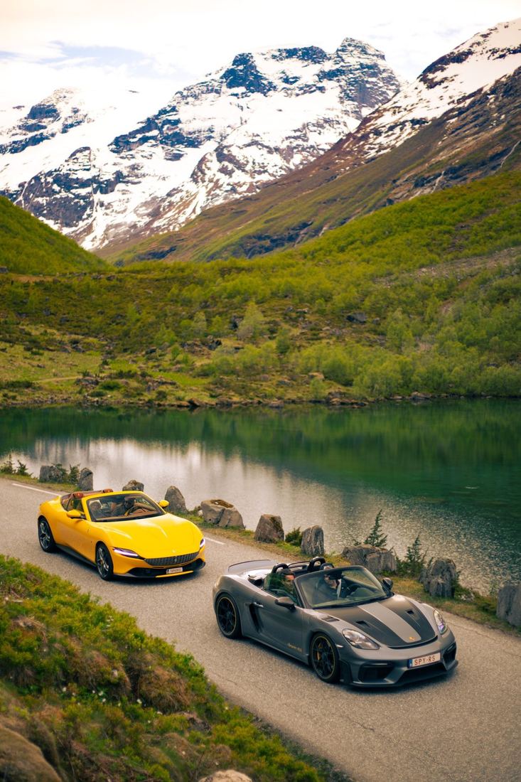 Gele Ferrari en Porsche Spyder langs een groen bergmeer