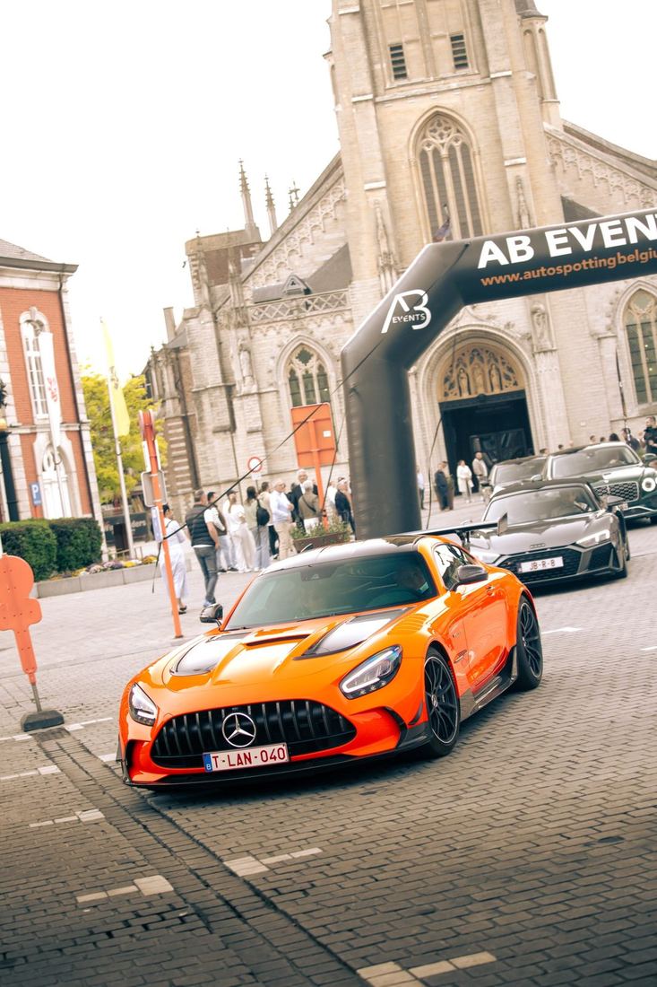 Oranje Mercedes-AMG rijdt onder de AB Events-boog voor de kerk van Sint-Truiden
