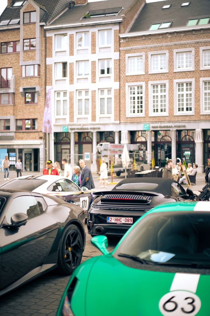 Ferrari, Porsche en een groene sportwagen met nummer 63 op de markt
