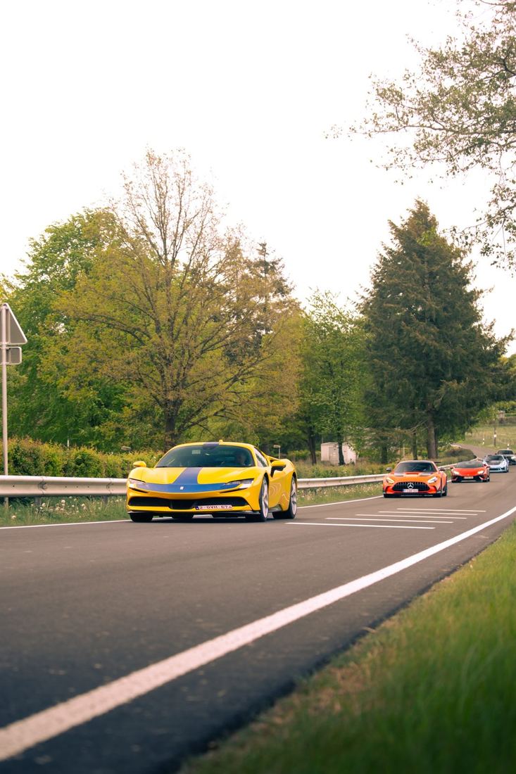 Gele Ferrari SF90 voorop een colonne op een landweg