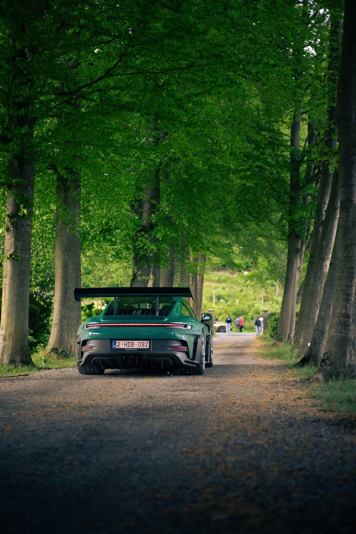 Groene Porsche GT3 RS rijdt door een bomenlaan