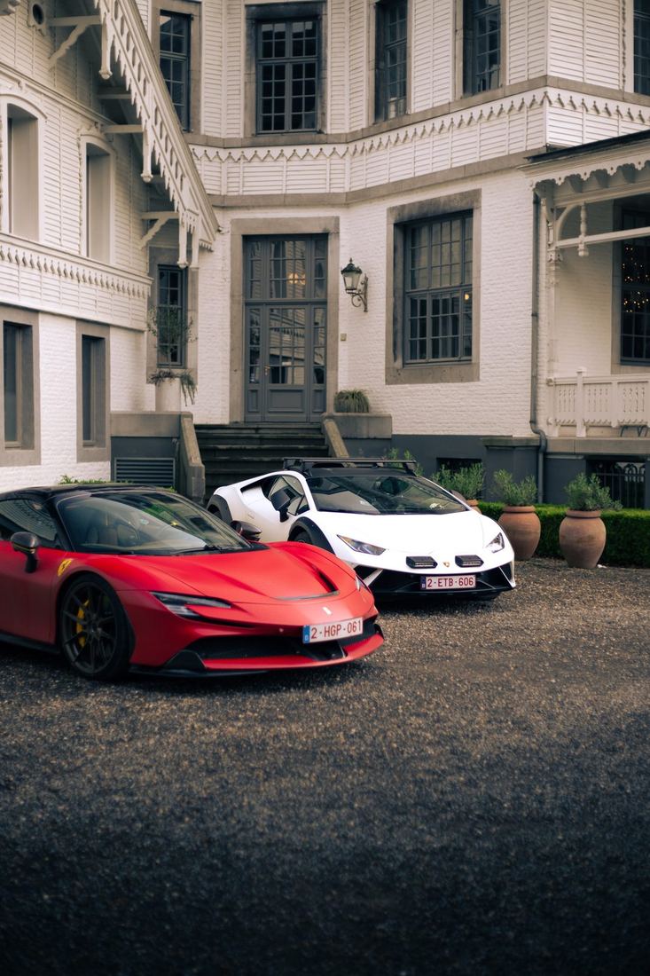 Rode Ferrari SF90 en witte Lamborghini voor het witte kasteel