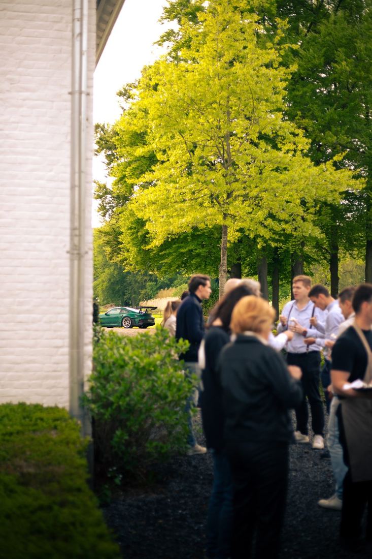 Apero met de groene Porsche op de achtergrond