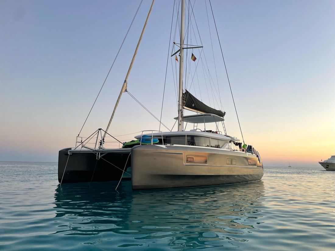 Catamaran voor anker bij zonsondergang