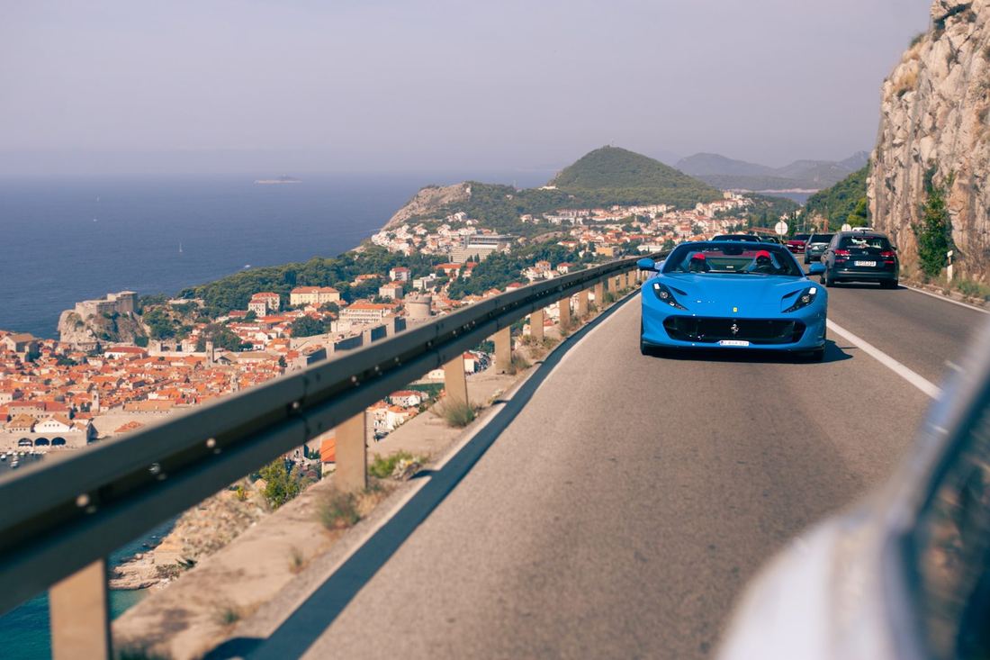 Blauwe Ferrari 812 GTS op de kustweg boven de oude stad van Dubrovnik