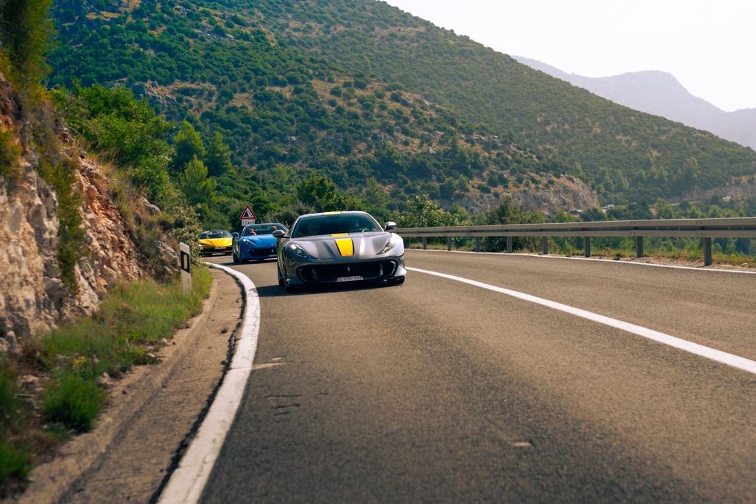 Grijze Ferrari 812 Competizione voorop een colonne in een bocht