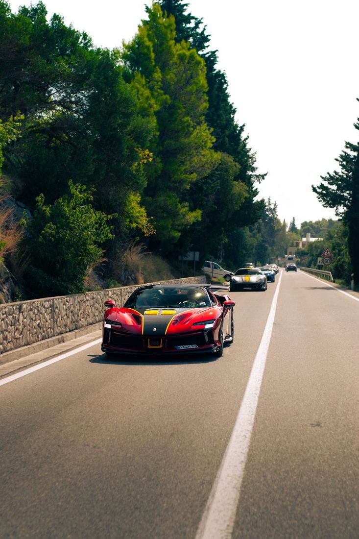 Rode Ferrari SF90 XX voorop de colonne langs de kust