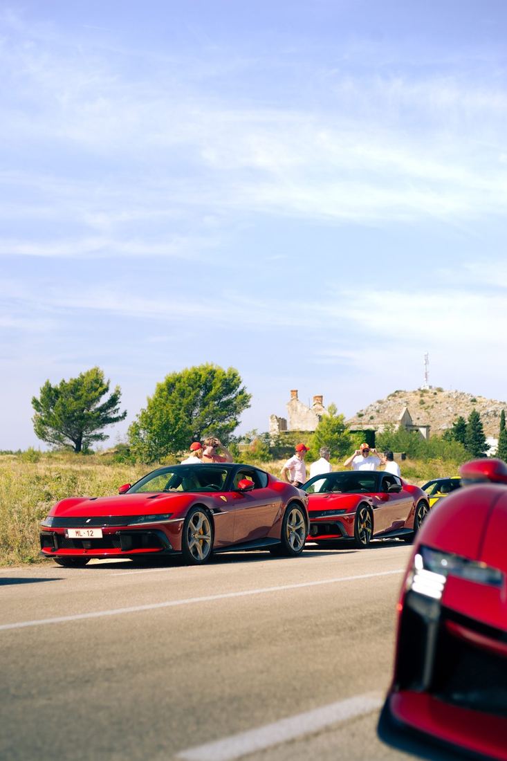 Deelnemers bij hun Ferrari’s langs de weg