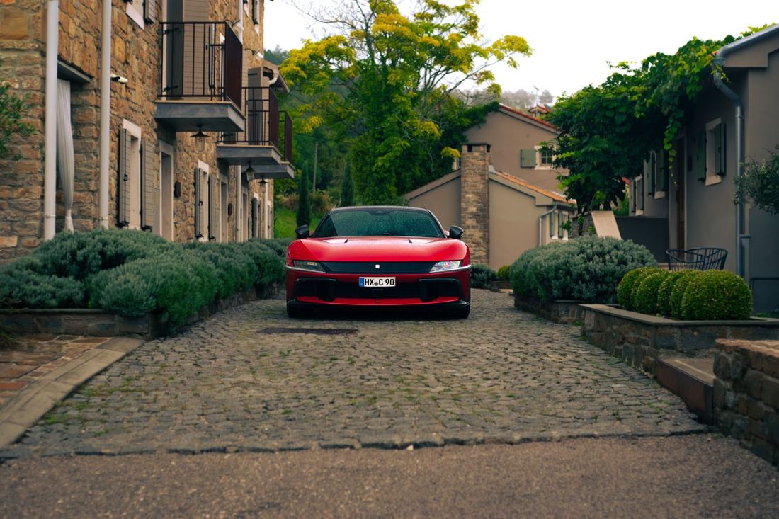 Rode Ferrari 12Cilindri tussen stenen huizen in Istrië