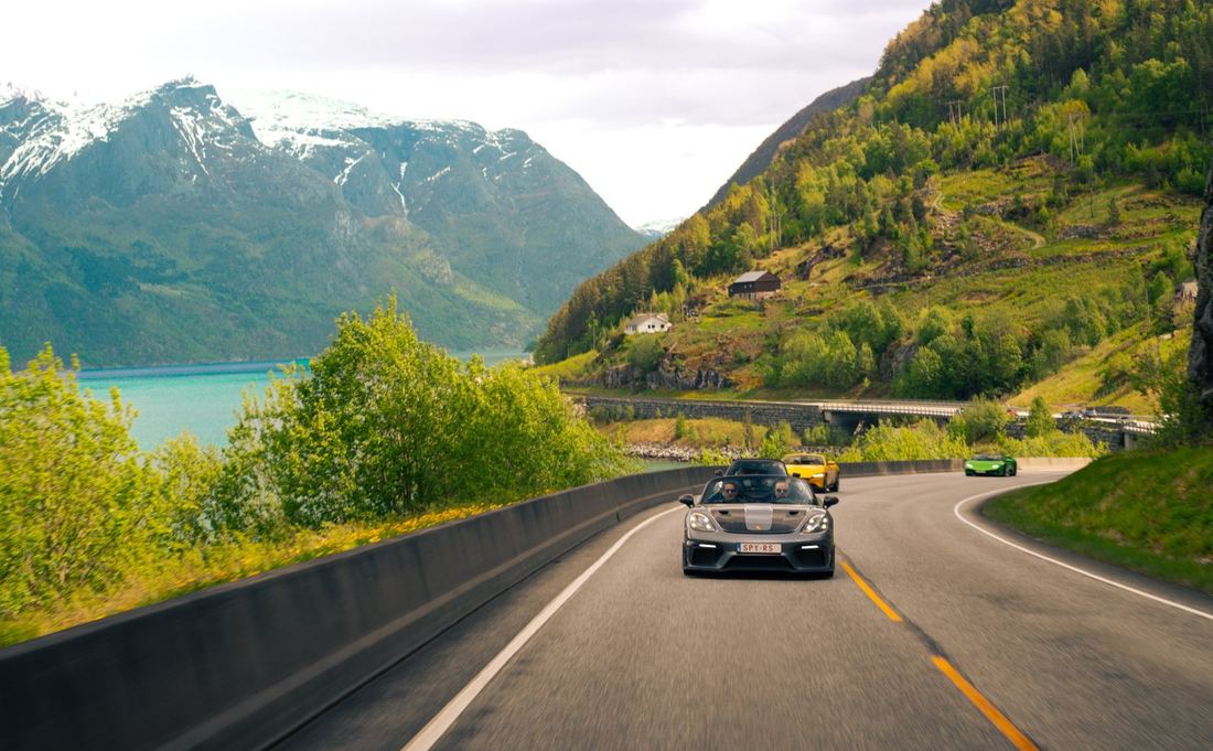 Supercars op een weg langs een fjord